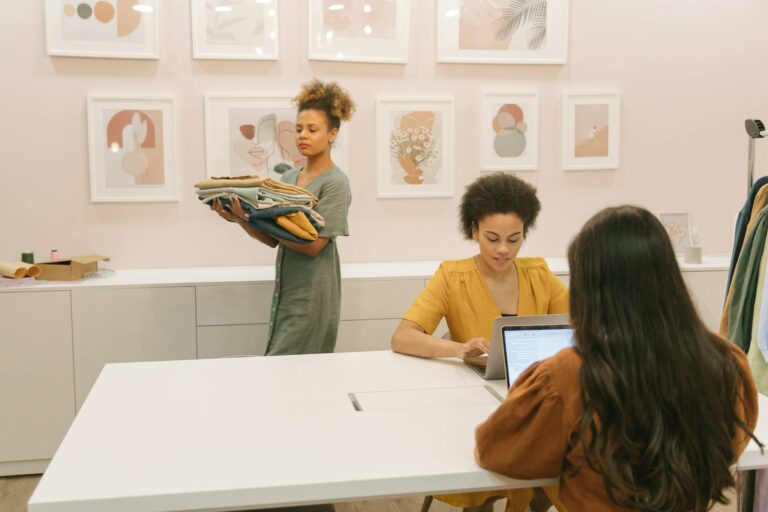 Three women working together in a stylish office setting, focusing on teamwork and clothing business.